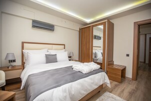 Una habitación de hotel moderna con una cama grande, mesitas de noche, un espejo y un equipo de aire acondicionado.