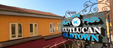 A sign for Kutlucan Oldtown hotel with a red awning and a street view below.