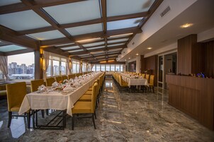 Una larga mesa dispuesta para un banquete, con vistas a la ciudad a través de amplias ventanas.