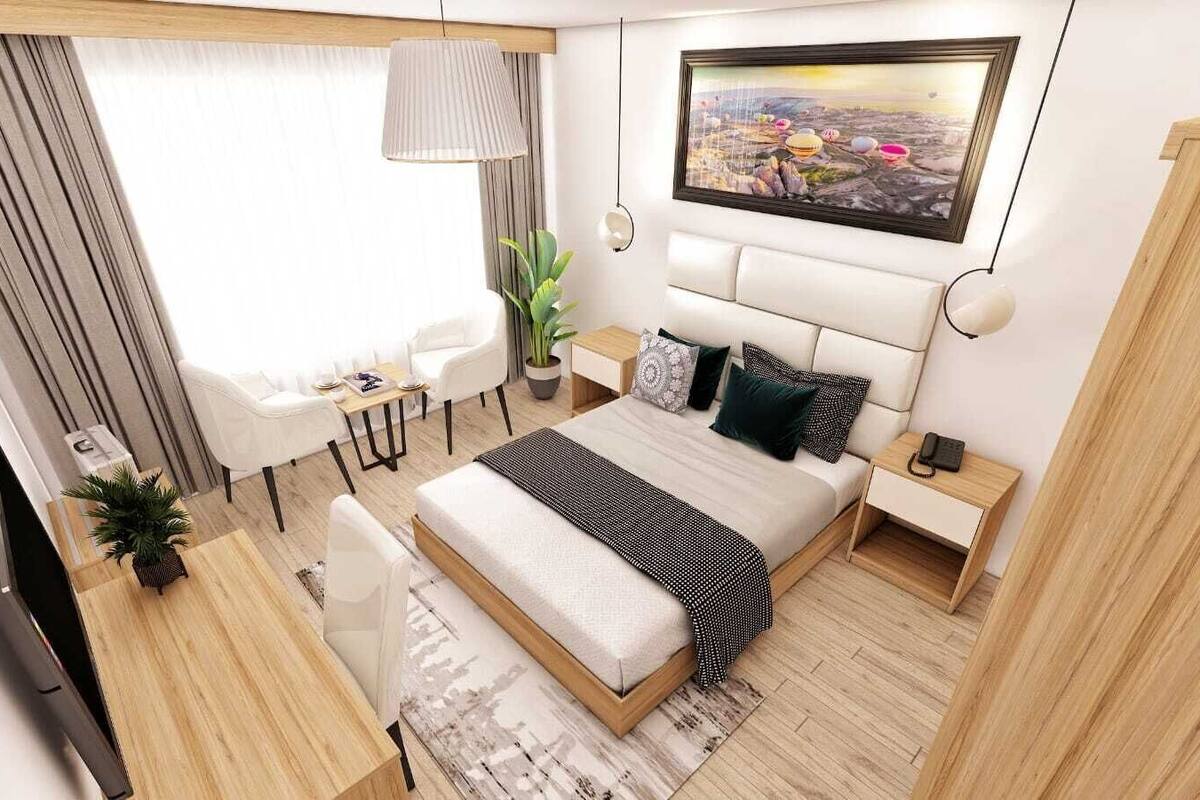 Una habitación de hotel moderna con cama, escritorio, silla, televisor y un amplio ventanal.