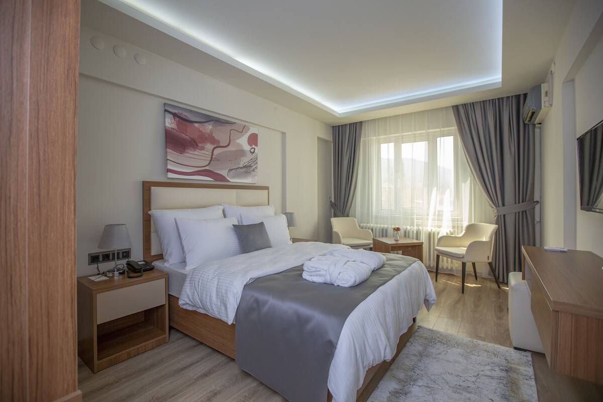 Una habitación de hotel moderna con una cama grande, mesitas de noche, un escritorio y una silla.