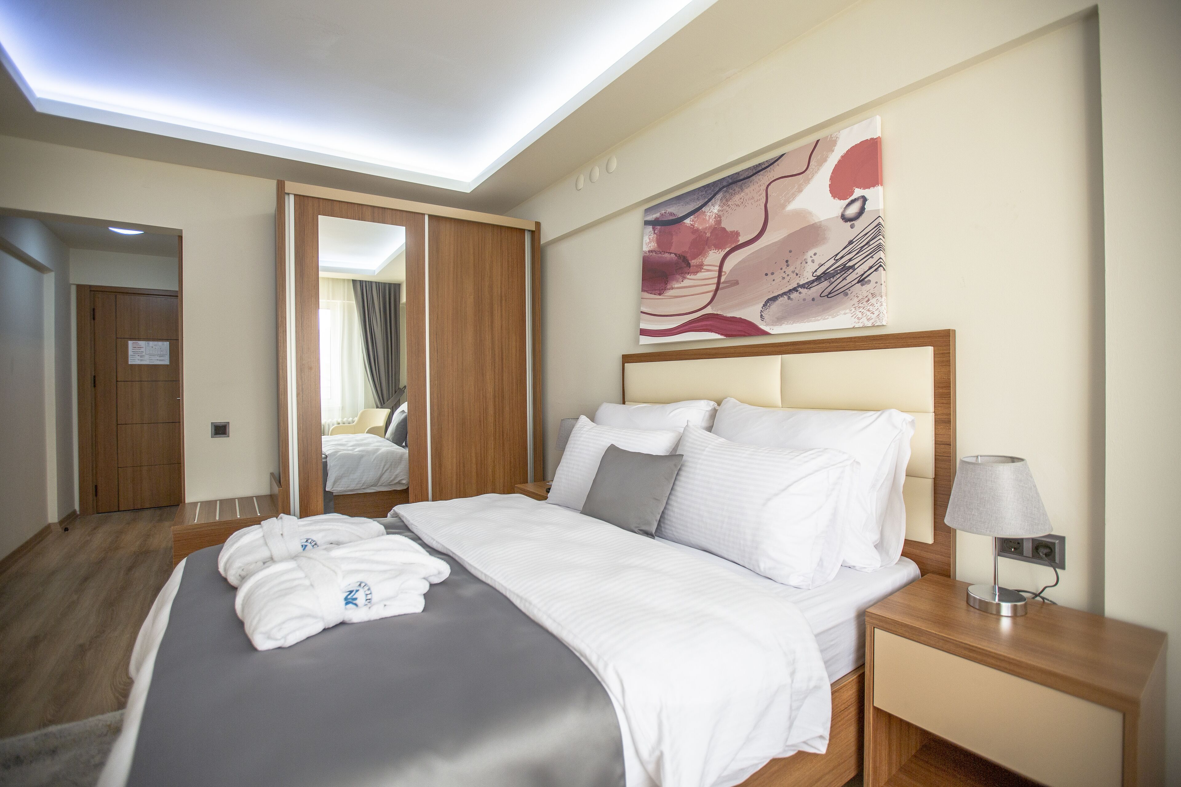 Une chambre d’hôtel avec un lit, une table de chevet, une lampe et un tableau au mur.