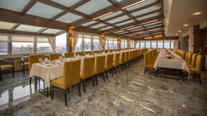 A long dining table set with chairs, a city view through large windows, and a high ceiling with wooden beams. - Kutlucan Oldtown Hotel (Bursa)
