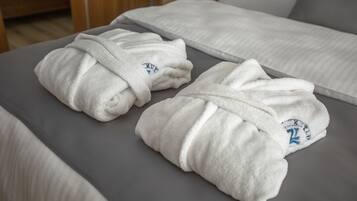 Dos albornoces blancos con un logotipo sobre la cama.
