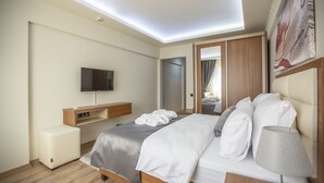 A modern hotel room with a bed, a TV, a bedside table, and a mirror. - Kutlucan Oldtown Hotel (Bursa)