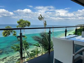 A balcony with a view of a turquoise sea and a clear sky.