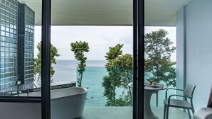 A modern bathroom with a bathtub, a glass-enclosed shower, and a view of the sea. - Cliff Lanta Suite (Ko Lanta)