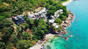 An aerial view of a coastal property with multiple houses surrounded by dense greenery and a clear blue sea. - Cliff Lanta Suite (Ko Lanta)
