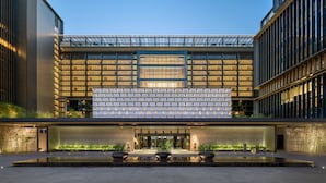 A modern building with a glass facade, a patterned facade, and a water feature in front.