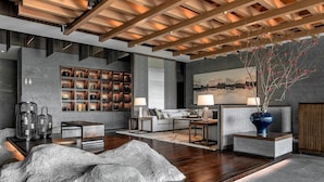 A modern living room with a wooden ceiling, a fireplace, a sofa, a coffee table, and a decorative vase.