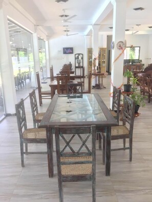 A spacious dining area with a glass-top table surrounded by wooden chairs with woven seats. - Saman Resort (Thissamaharama)