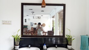 Un bagno con due lavandini, uno specchio e il cartello delle toilette.