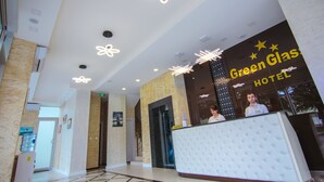 A hotel reception area with a modern design, including a reception desk, a large glass window, and decorative ceiling lights. - Hotel Green Glass (Batumi)