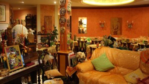 A room with a sofa, a table with various items, and a wall with framed pictures. - Tilly's B&B (Le Hohwald)