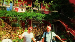 A building with a red exterior, multiple windows, and balconies with potted plants. - Tilly's B&B (Le Hohwald)