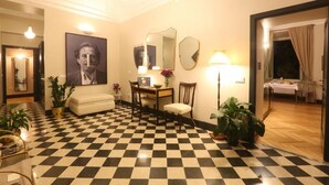 A hotel lobby with a checkered floor, a sofa, a dining table with chairs, a mirror, and a lamp. - Santa Monica Townhouse (Rome)