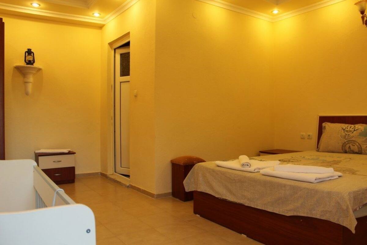 A bedroom with a bed, a nightstand, a bedside table, a lamp, and a door.