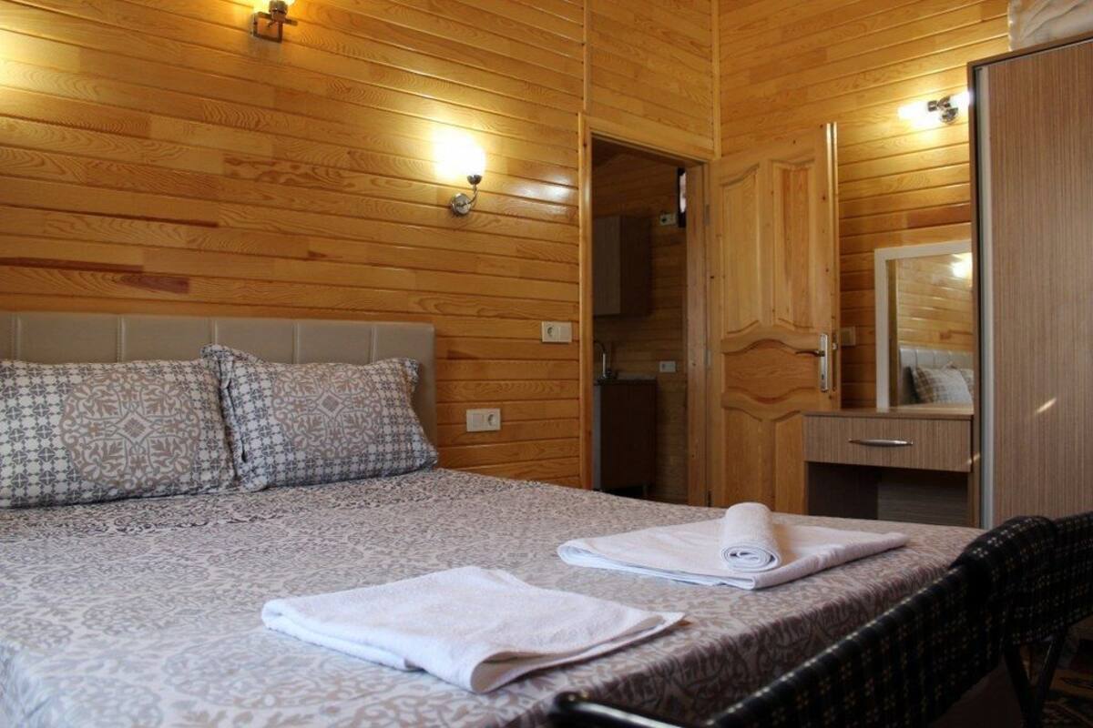 A wooden-paneled room with a bed, a chair, and a mirror.