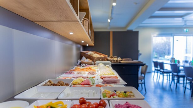 En buffet med forskellige retter og et siddeområde med borde og stole.