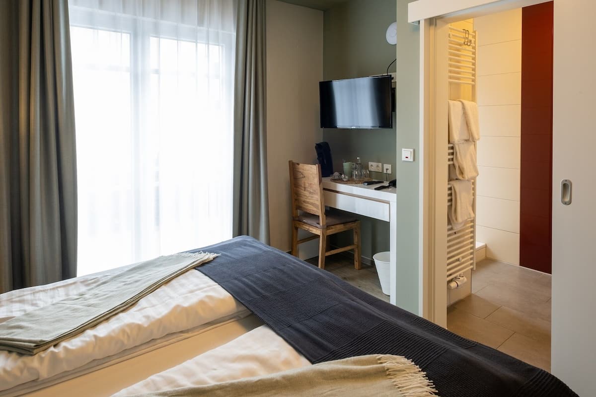 Une chambre d’hôtel comprenant un lit, un bureau avec une chaise, une télévision et une salle de bain avec un porte-serviettes.