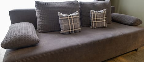 A brown sofa with three pillows, two of which have a plaid pattern.