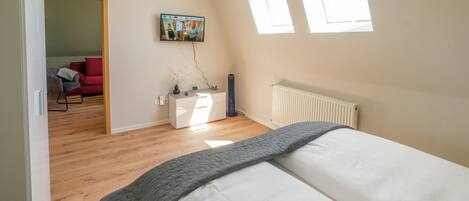 A bedroom with a bed, a desk, a chair, and a radiator.