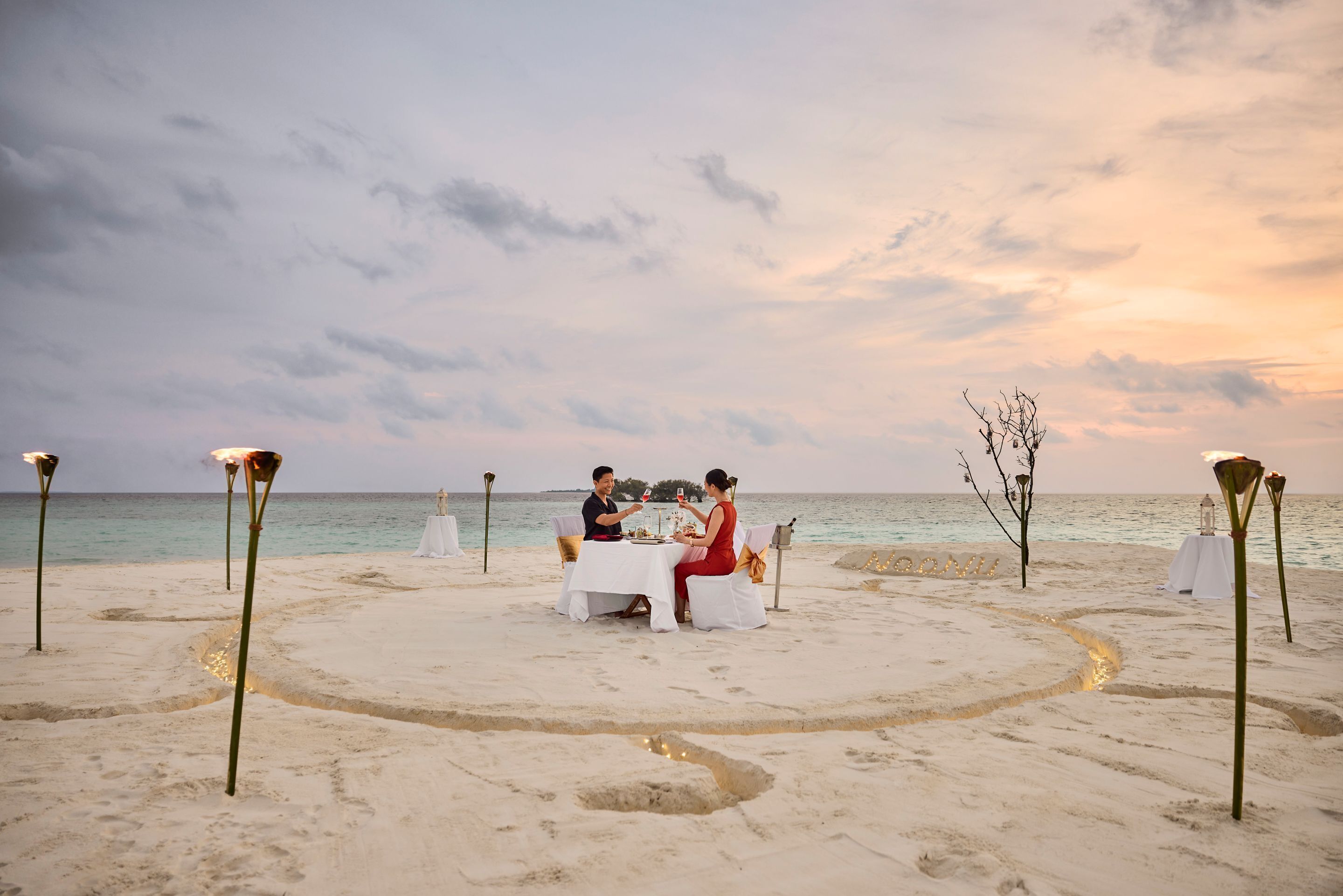 Un montaje para comer frente al mar, con una mesa y sillas, rodeado de iluminación decorativa.