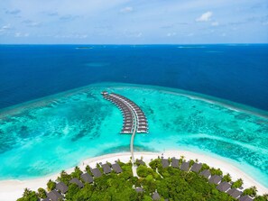 An aerial view of a resort with overwater bungalows connected by a walkway, surrounded by turquoise waters and a white sandy beach. - ROBINSON NOONU - All inclusive (Orivaru)