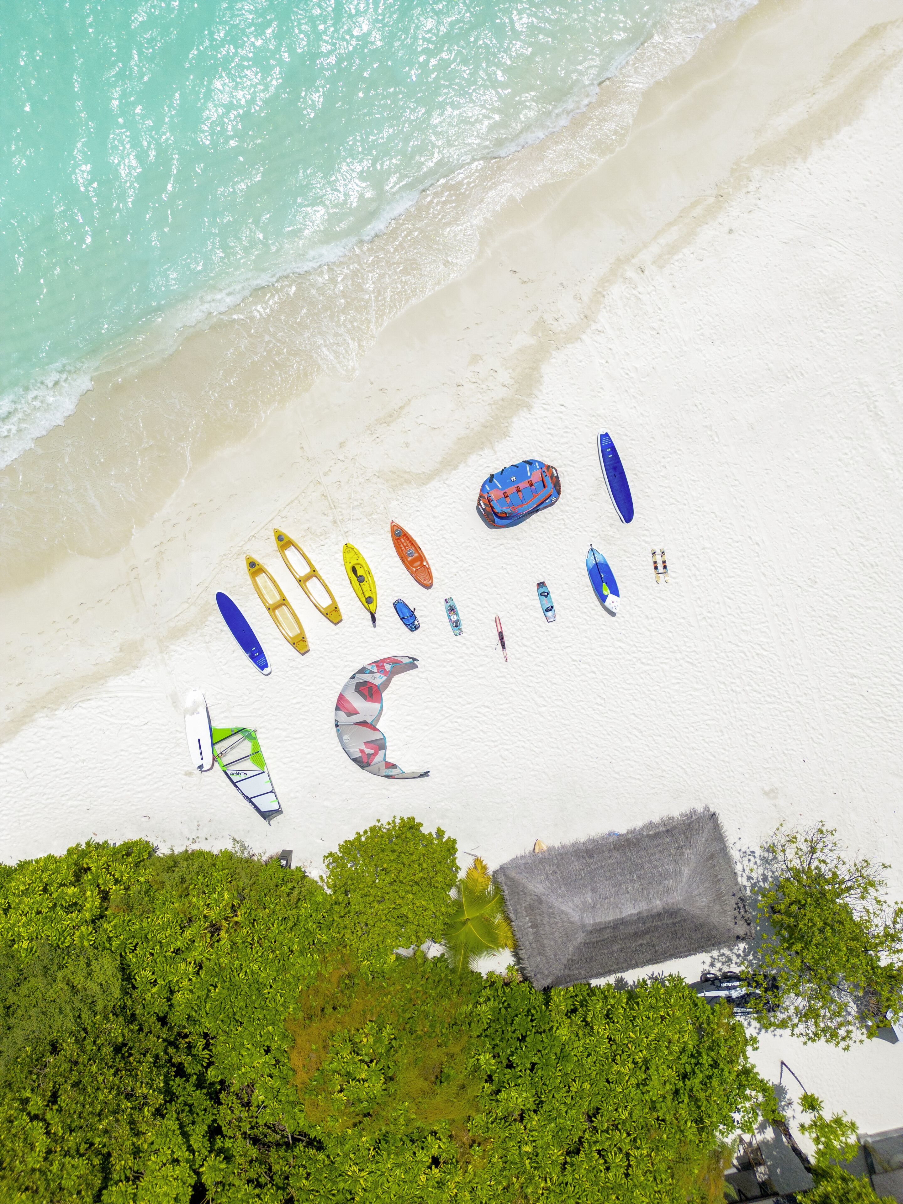 Une plage où l’on peut voir différents types d’embarcations et une structure recouverte de chaume.