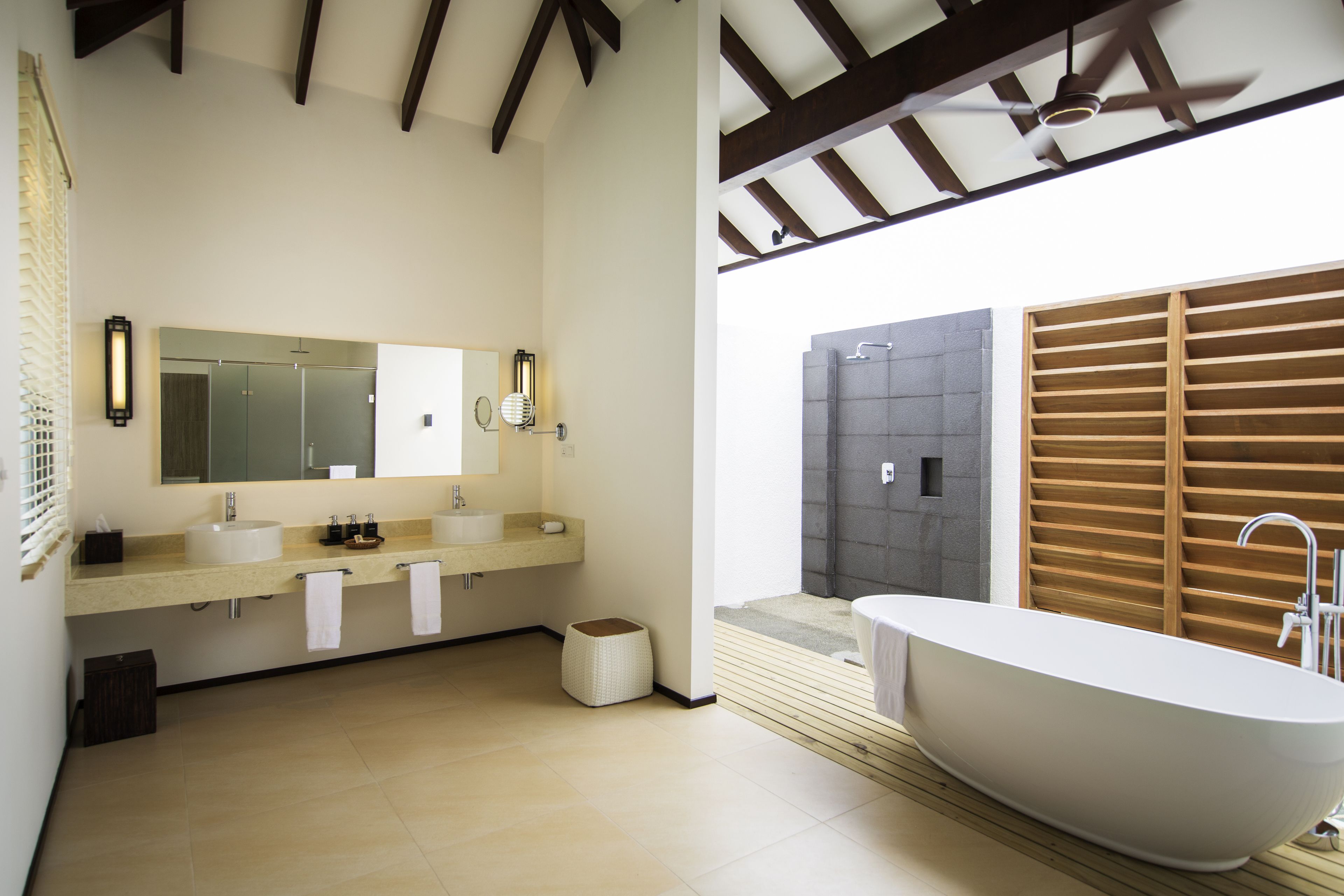 Un baño moderno con una bañera independiente, un espejo grande y un mueble de tocador con dos lavamanos.