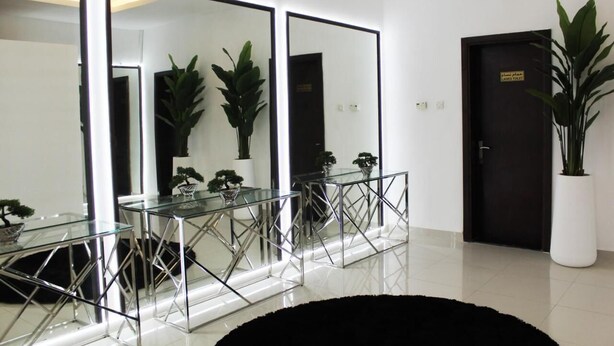 Un interior moderno con tres espejos grandes, una mesa de vidrio con patas metálicas y plantas en macetas.