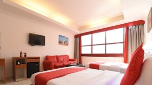 Habitación de hotel con una cama grande, un sofá, un escritorio y un televisor.