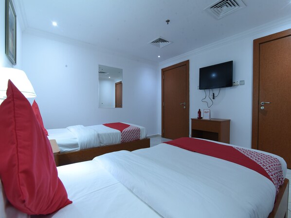 Habitación de hotel con dos camas, un televisor, un espejo y un armario.