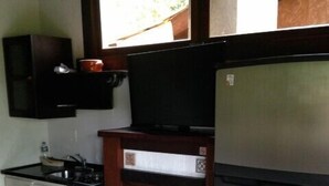 A compact kitchen with a refrigerator, stove, and sink. - Pousada Aloha Beach House (Imbituba)