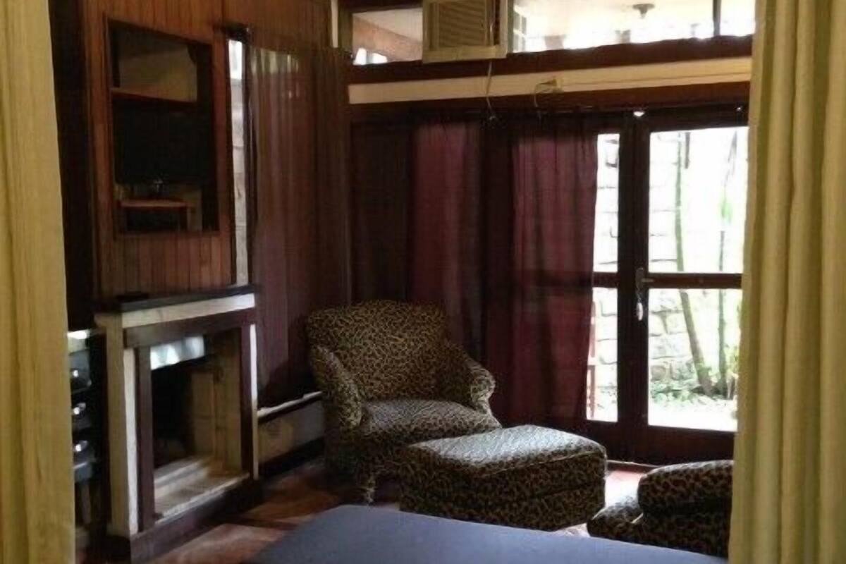 Une pièce comprenant un lit, un pouf à motifs léopard, une chaise, une cheminée et une fenêtre avec des rideaux.