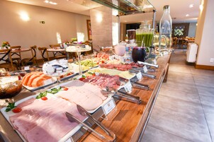 Un buffet con diverse carni, formaggi e insalate.
