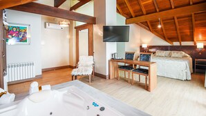 A spacious room with a large wooden ceiling, a bed, a sitting area with chairs, a large bathtub, and a flat-screen TV mounted on the wall. - Hotel Refúgio da Montanha - 900m da Rua Coberta (Gramado)