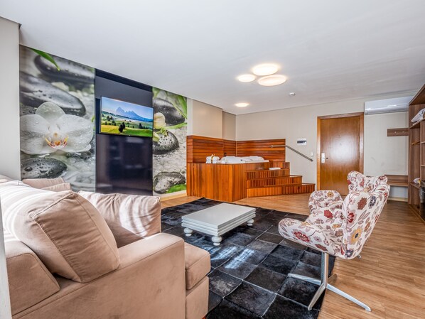A modern living room with a sofa, a patterned armchair, a wooden reception desk, and a wall with nature-themed artwork.