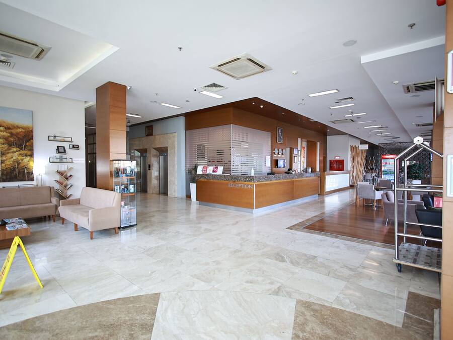 A hotel reception area with a reception desk, seating area, and a large painting on the wall.
