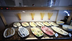 Um buffet com diversos alimentos e utensílios.