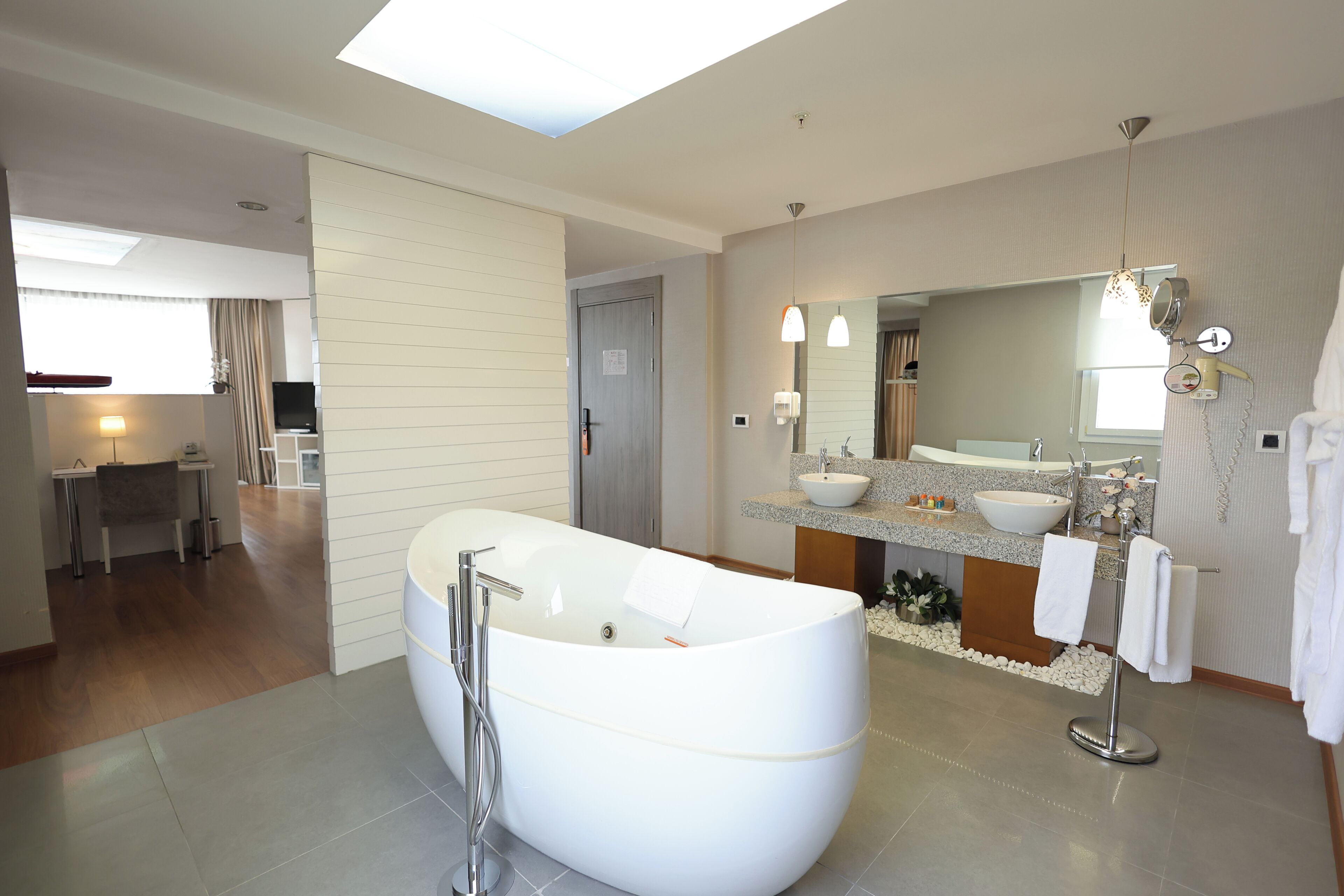 Ein modernes Badezimmer mit einer freistehenden Badewanne, einem großen Spiegel und einem Waschtisch mit Waschbecken und Handtuchhalter.