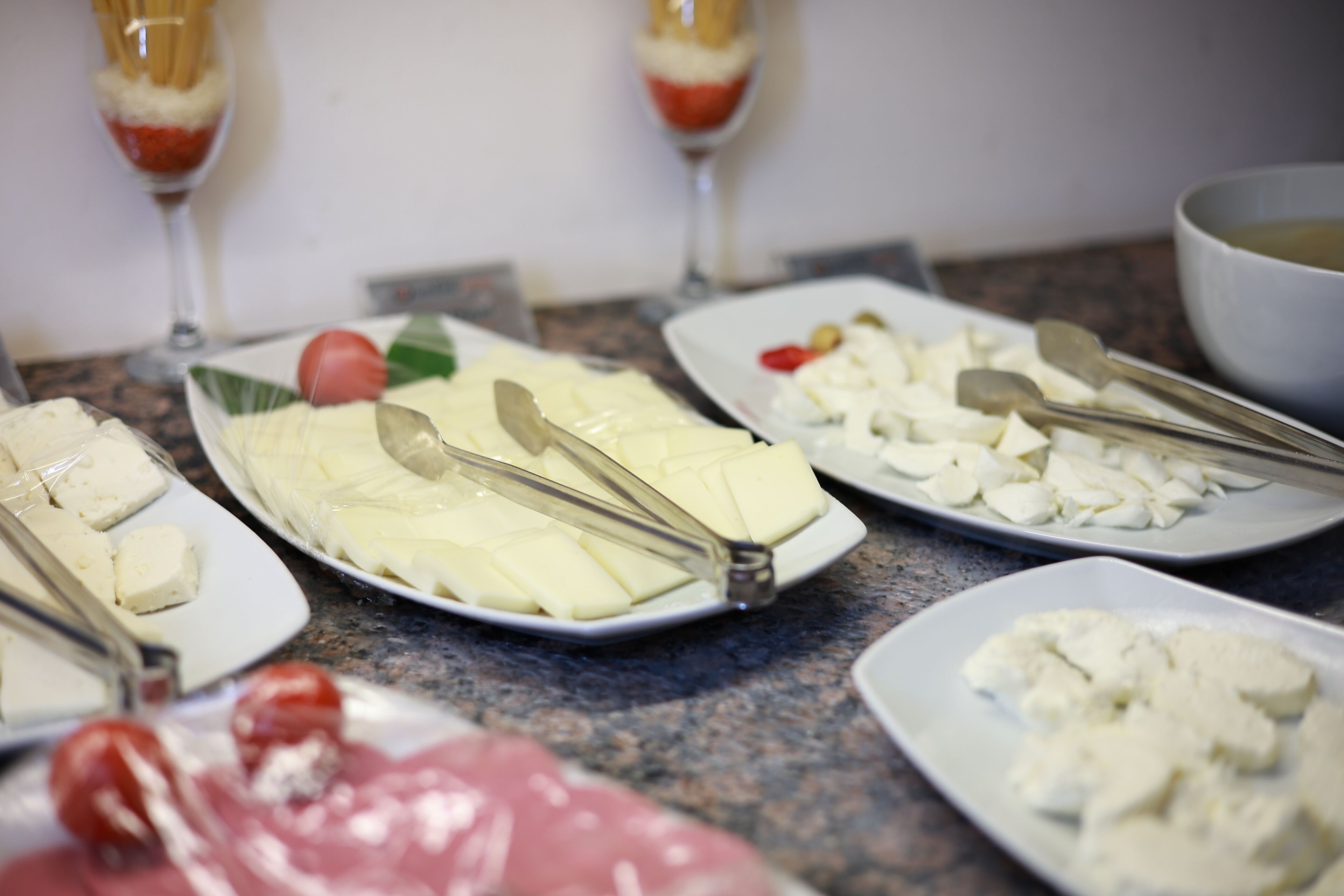 Un bufé con diferentes alimentos, como queso, tomates y aceitunas, en platos.