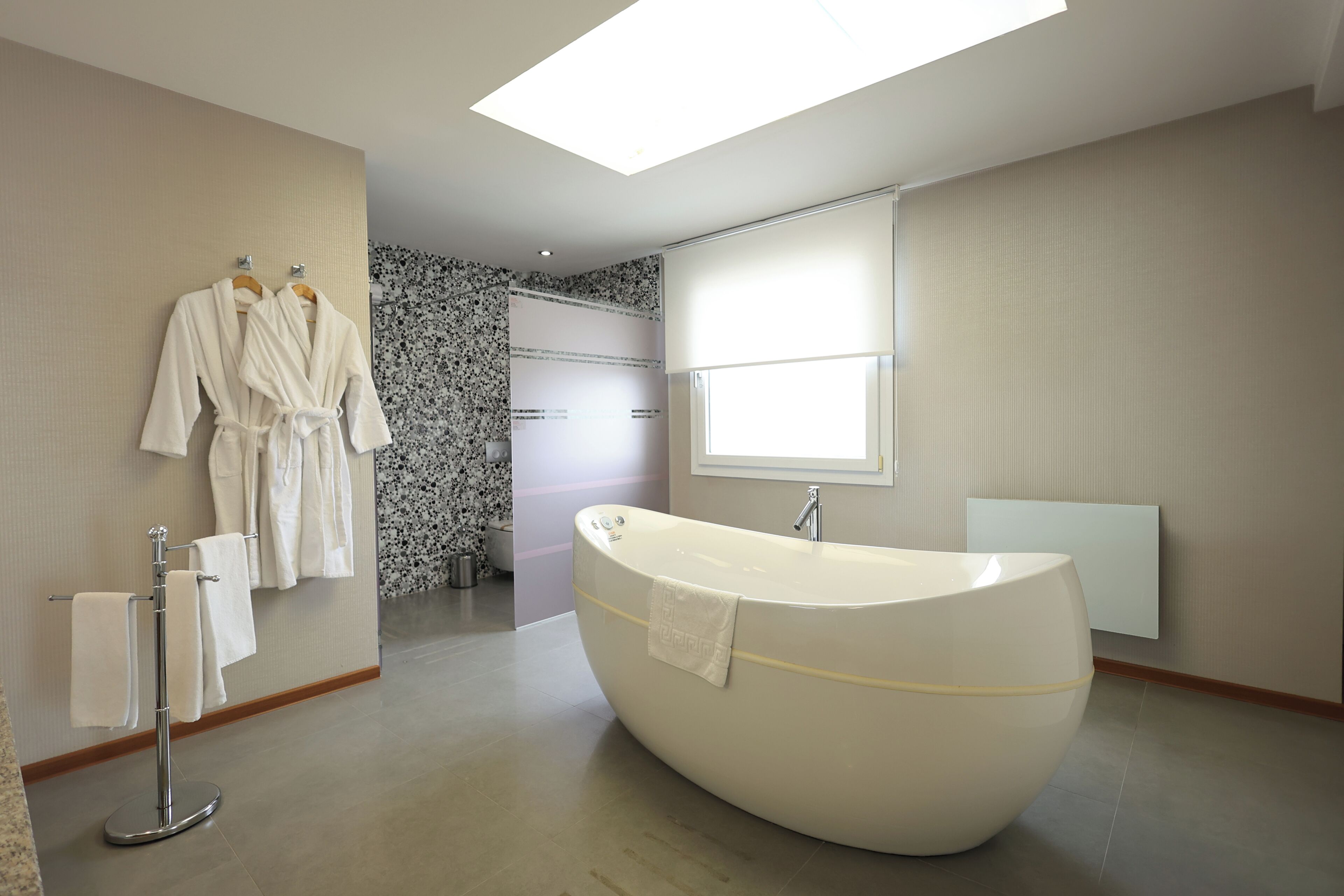 Une salle de bain moderne avec une baignoire sur pieds, un porte-serviettes avec des peignoirs et un espace douche.