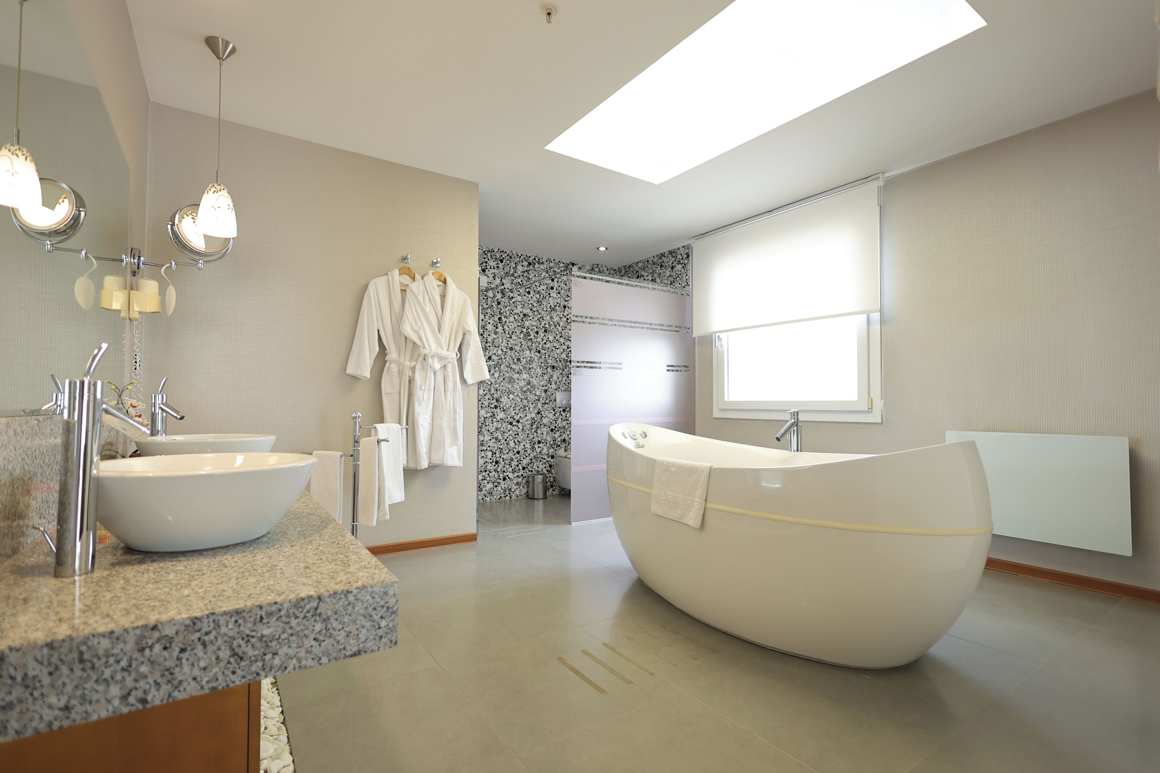 Un baño moderno con una bañera independiente, un espejo grande y una encimera de granito.