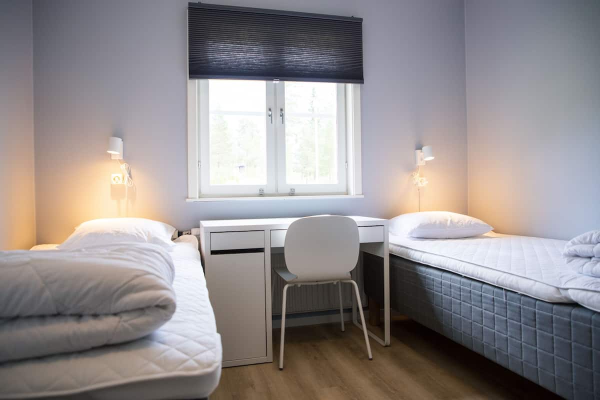 A bedroom with two beds, a desk, and a chair.