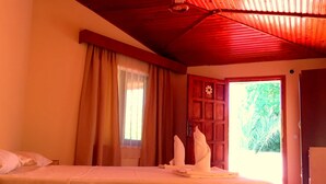 Una habitación con cama, una puerta de madera y una ventana con cortinas.