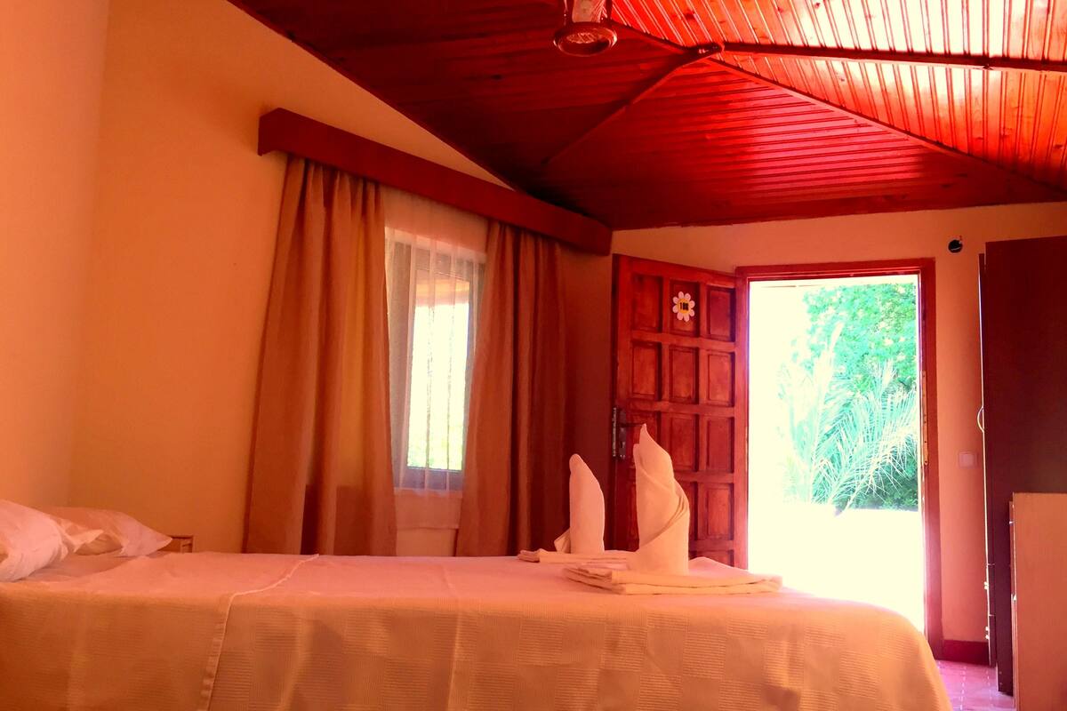 A room with a bed, a wooden door, and a window with curtains.