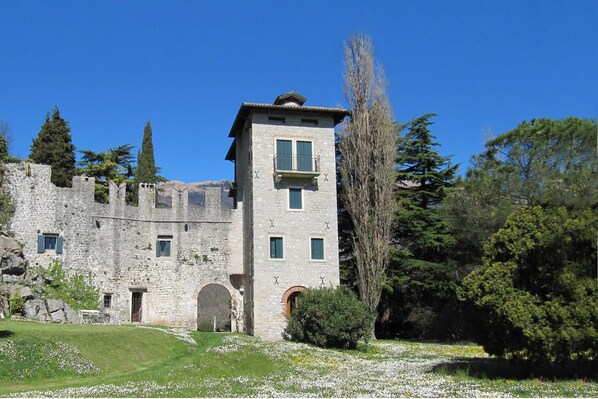 A stone castle with a tower, arched entrance, and a small balcony.