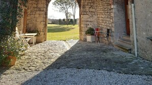 Un'entrata ad arco in pietra conduce a un cortile verde.