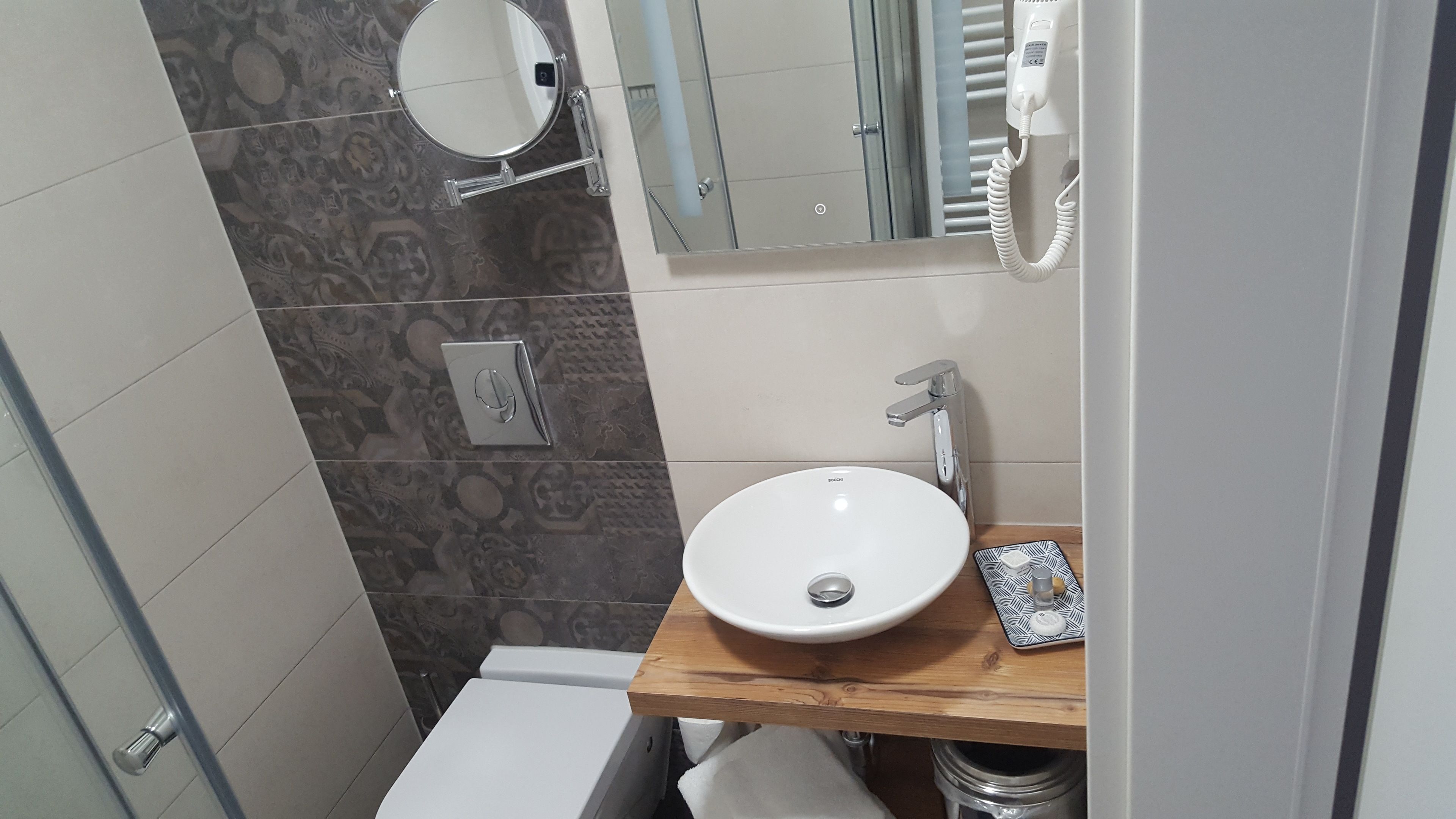 Een badkamer met een witte wastafel, een spiegel, een haardroger en een toilet.